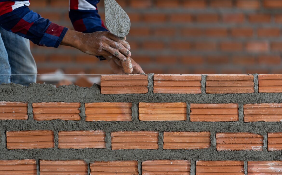 Closeup hand professional construction worker laying bricks in n