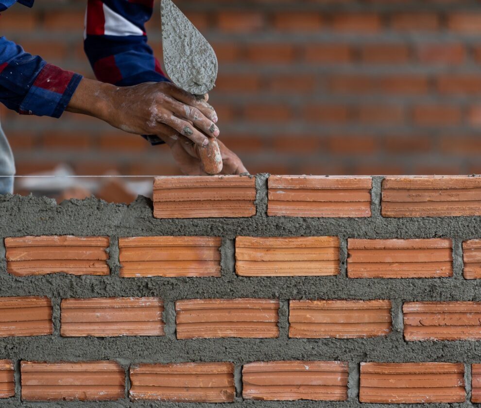 Closeup hand professional construction worker laying bricks in n